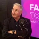 Stephen Robinson sits in front of a purple screen that reads Face to Face with Chancellor May